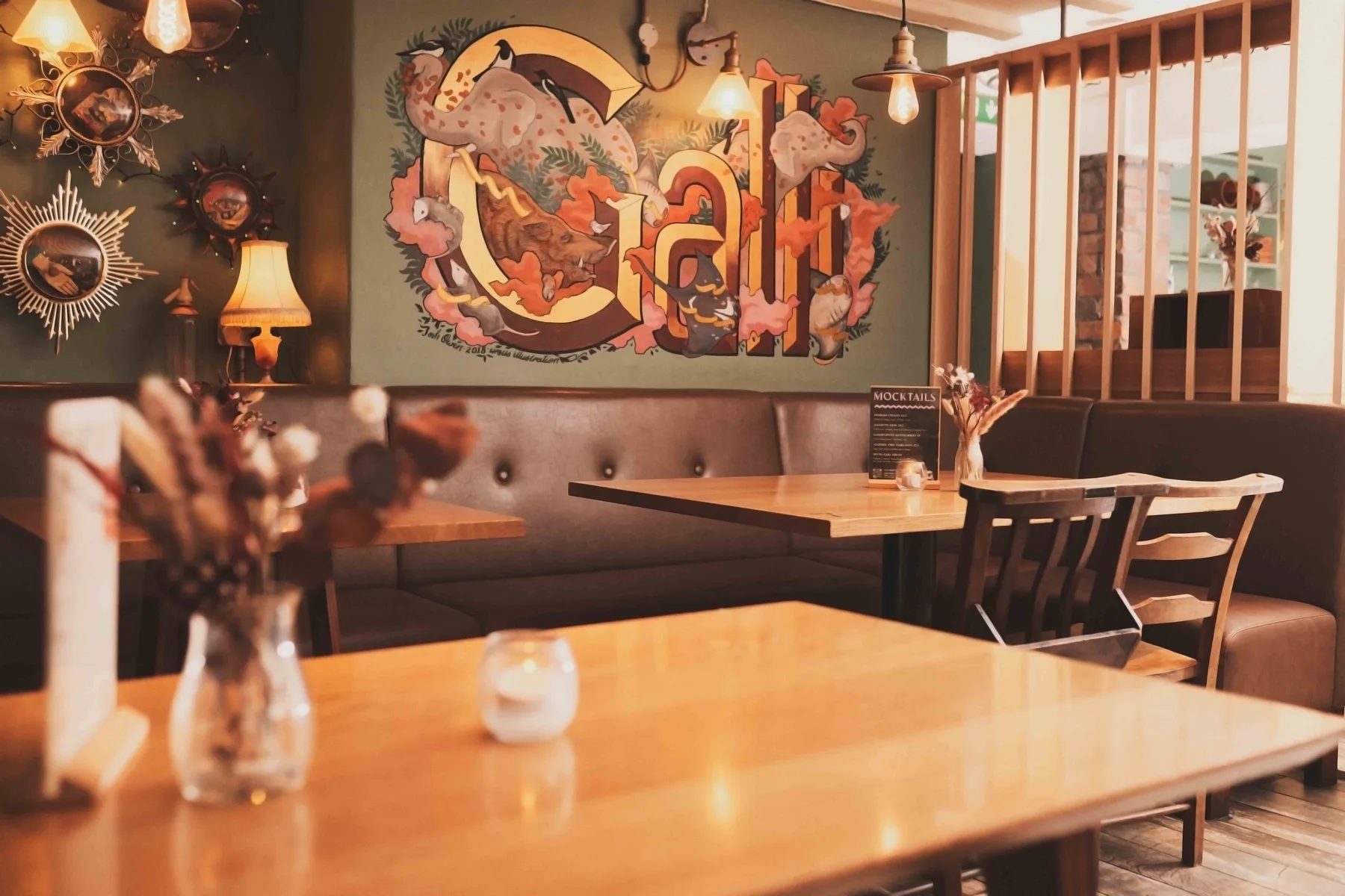 The Gallimaufry interior with its mural, warm lighting and wooden tables